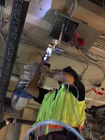 Electrician with the CP1000 Cordless Drill Powered Handheld Wire Puller pulling multiple wires through conduit & into a ceiling junction box.